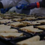 a group of people in gloves holding trays of food